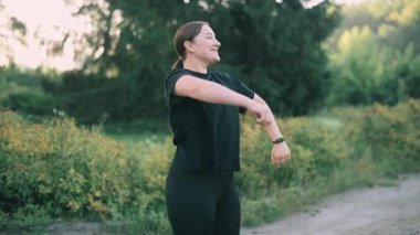 Orta yaşlı bir kadın parkta sabah antrenmanından önce ısınıyor..