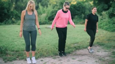 Parkta spor yapan üç orta yaşlı kız arkadaş. Ön görünüm.