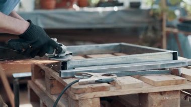 Bir atölyede metal çerçeve öğütücü ile çalışan işçiler, kıvılcımlar, işçilik ve endüstriyel metal işçiliği gösteriyor..