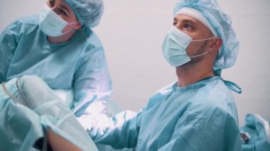 Doktor özel ekipmanlarla jinekolojik ameliyat yapıyor. Cerrah ekrana bakar..