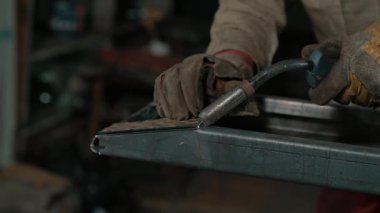 Meşale endüstriyel bir tezgahta çeliği kaynatırken parlak kıvılcımlar uçuşan kaynak yapan bir işçinin yakın çekimi. Yavaş çekim.