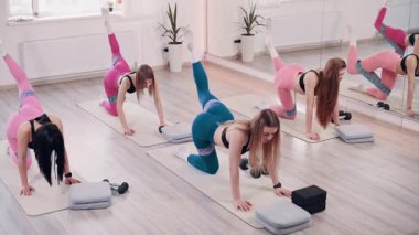 Beden eğitiminde grup çalışması. Bir grup narin genç kadın fitness bantlarıyla antrenman yapıyor..