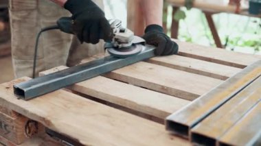 Bir işçi, çelik bir parçanın pasını öğütücüyle öğütüyor. Yakın plan..