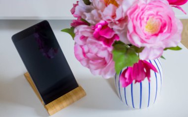 Çiçek vazosunun yanındaki dairede masanın üzerinde duran telefon.