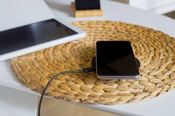 the phone lying on the wireless charger next to the tablet
