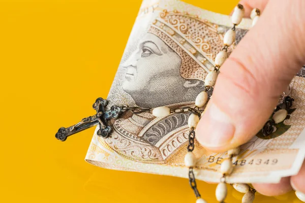 Christian rosary hand-held with money. Concept of church business and corolla. Polish two hundred zlotys