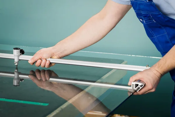 Camcı, cam paneli profesyonel bir aletle keser.