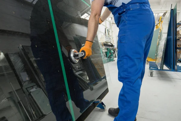 Camcı, iş yerindeki profesyonel bir masada özel bir vakum kabıyla cam levhayı kavrıyor.