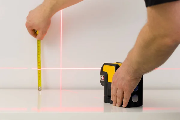 the worker marks right angles and lines during interior measurements