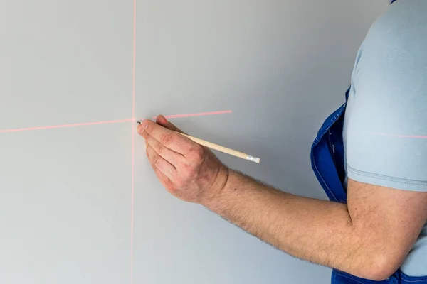 A specialist marks a point on a wall with an electronic laser