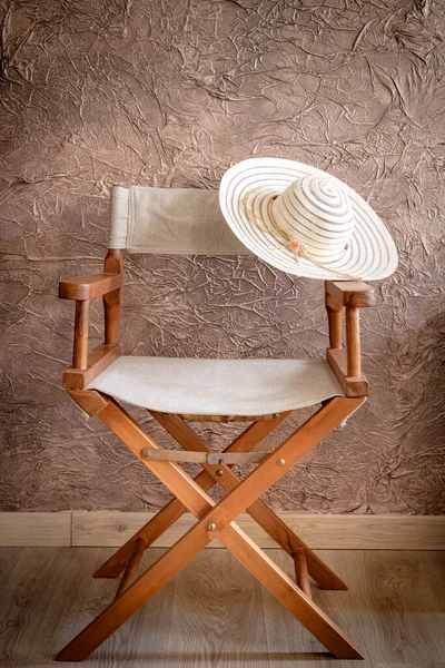 Director chair with a striped on the basis, an elegant womens hat, Vintage style. empty place