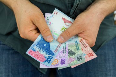 Adam elinde Arjantin pezosu tutuyor.,