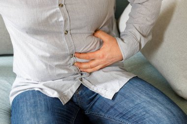 Tişörtlü bir adam apandisitinin etrafında ağrıyan bir mide hisseder. 