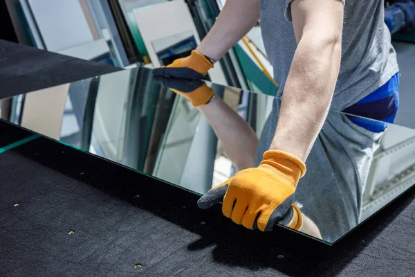 Camcı masadan bir ayna parçası alıyor. Cam fabrikası, üretim. 