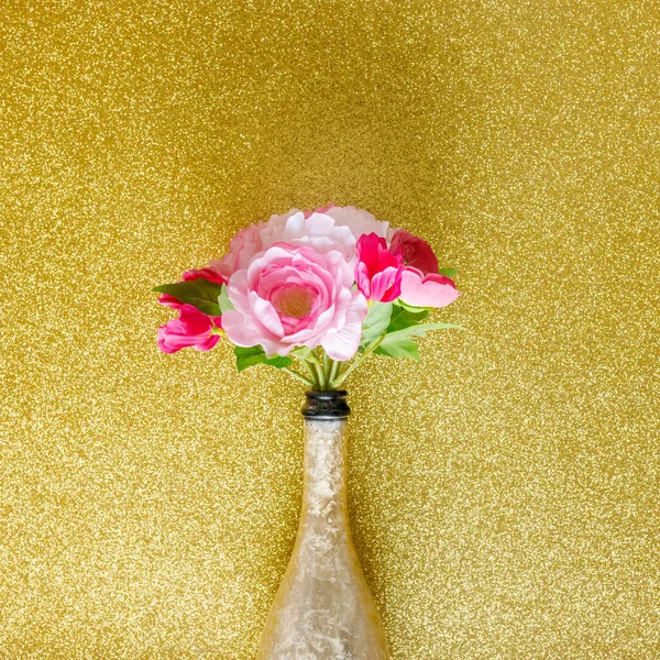 bouquet of flowers in a bottle of champagne. shiny gold background, creative, minimal party composition, celebration layout