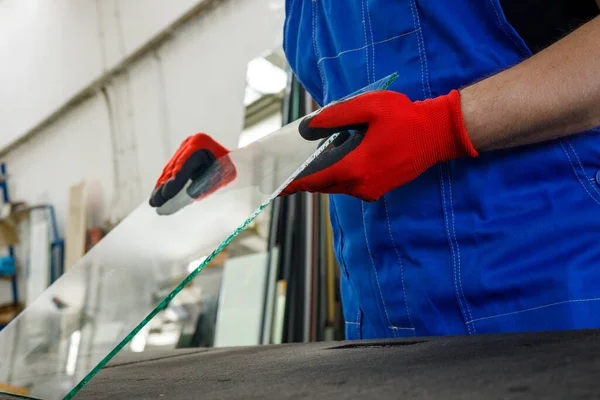 Cam fabrikası, camcı elinde bir cam parçası tutuyor. 