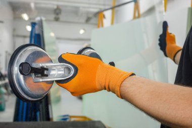 Camcı pencere için bir enayi kullanıyor. Cam atölyesi, bir adam özel aletlerle dolu kalın bir cam levha tutar. 