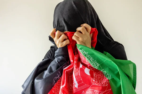 Desperate Woman in Traditional Afghan Dress Pressing Desperate Country Flag to Her Face, Concept, Afghan Women\'s Drama