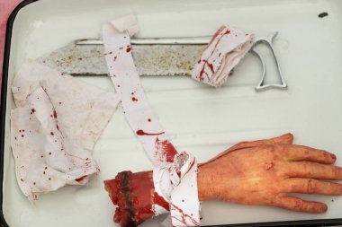 Yırtık bir yapay el tepside, kesme topunun ve kanlı paçavraların yanında, Cadılar Bayramı 