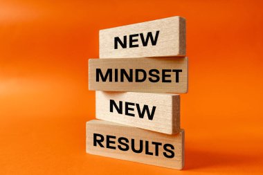 Yeni bir zihniyet, yeni sonuçlar. Kavram, kişisel ve iş geliştirme. Tahta bloklara yazılmış. Güzel turuncu arka plan. Kapat.