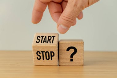 Başla ve Durdur sembolü ve bir soru işareti. Tahta bir bloğu çeviren bir el 