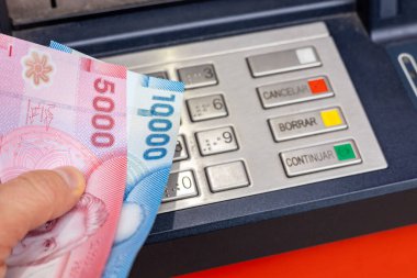 Elinde para olan bir Şilili ATM 'de duruyor. İş ve ekonomi kavramı. Şili finans. Kapat.