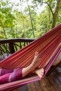 Tatil, ormanda dinlenme doğa ile çevrili. Orman kulübesinde hamakta yatan bir kadının bacakları..