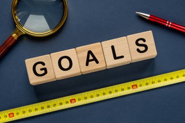 Hedefler. Tahta bloklara yazılmış kelime. Bir mezura hedefi belirler. Zarif bir lacivert arka plan. İş Konsepti.