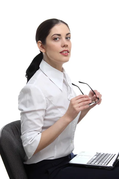 Le portrait d'une jeune femme d'affaires souriante assise sur la chaise de bureau, portant des lunettes dans ses mains et un ordinateur portable à genoux — Photo