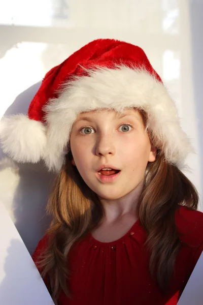 Портрет красивої здивованої маленької дівчинки в капелюсі Санта помічника на білому тлі — стокове фото
