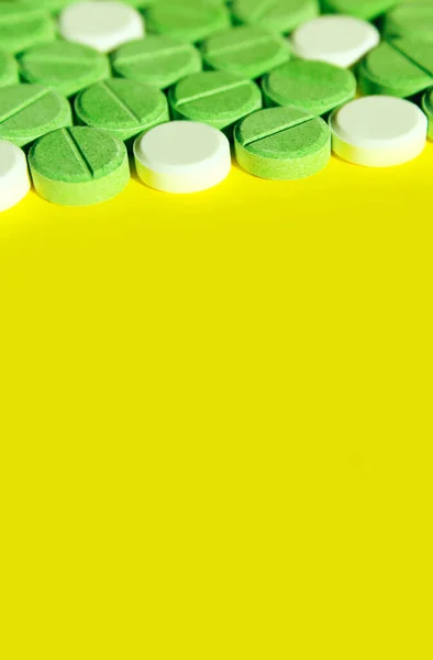 Colorful pills on yellow background, vertical banner.