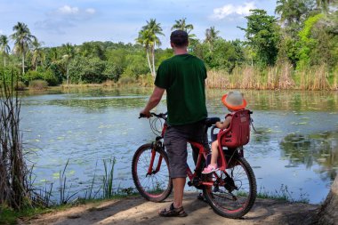 Baba ve kızı tropikal su birikintisi yakın bisiklet ile