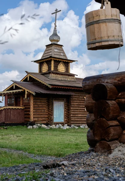 Wooden Church in Semiluzhenski kazak ostrog and wooden water wel — Stock Photo, Image