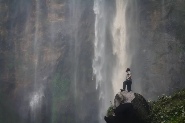 Şelalenin arka planında bir adam
