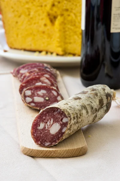 Salami slices on the table, wine and cheesy bread on background: traditional italian Easter brunch — Stock Photo, Image