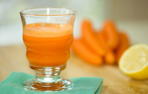Copo de suco de cenoura extraído de cenouras frescas — Fotografia de Stock