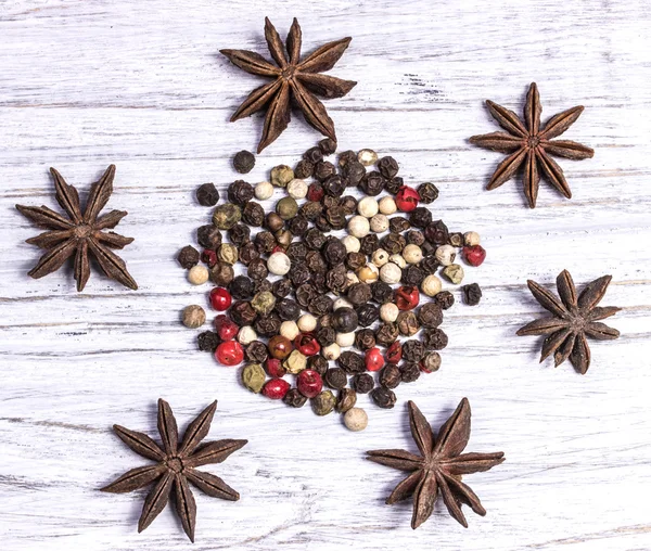 Una miscela di pepe nero peperoncino bianco, stelle di anice sul vecchio bordo bianco di legno — Foto Stock