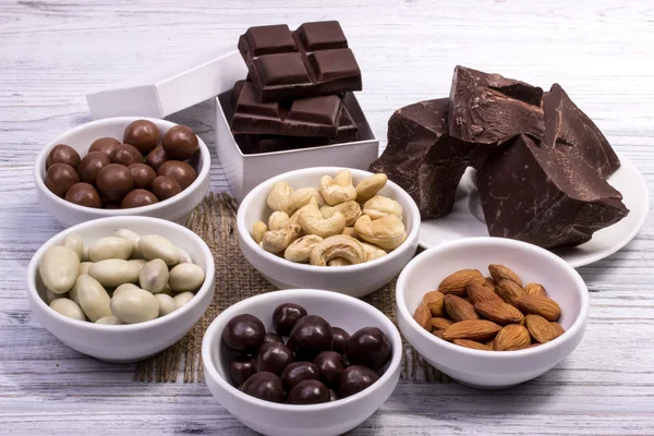 Schokolade, Bonbons, Rosinen, Nüsse in den einzelnen Schüsseln auf einem grauen Holzbrett — Stockfoto