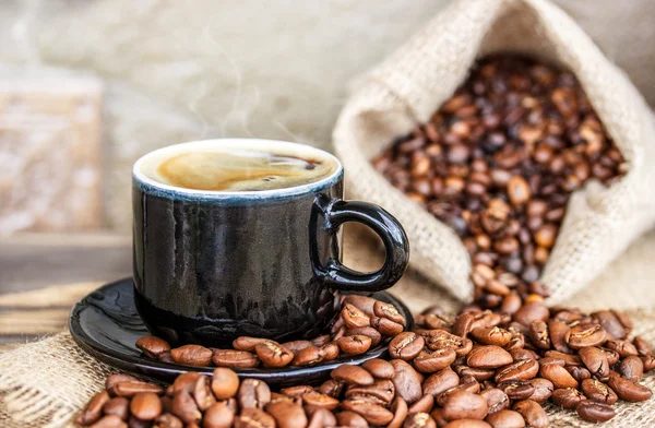 Granos de café en una tabla de madera y una taza de café —  Fotos de Stock