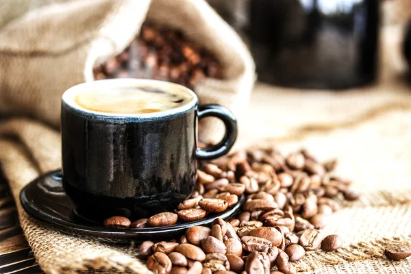 Granos de café en una tabla de madera y una taza de café —  Fotos de Stock