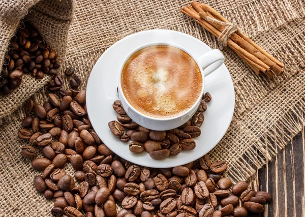 Grãos de café em uma tábua de madeira e uma xícara de café — Fotografia de Stock