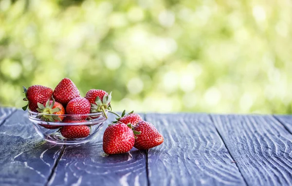 Red strawberries outdoors on an old table — Stock Photo, Image