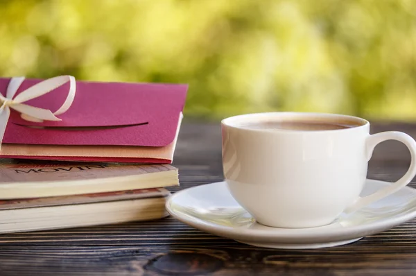Taza de café y un sobre sobre sobre una mesa de madera — Foto de Stock