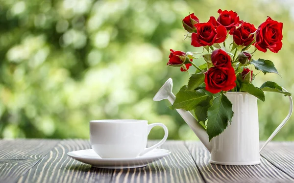 Taza de café y rosas rojas en una mesa de madera — Foto de Stock