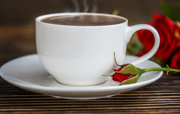 Taza de café y rosas rojas en una mesa de madera — Foto de Stock