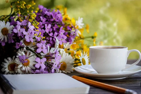 Carnet, fleurs et tasse de café sur le bureau — Photo