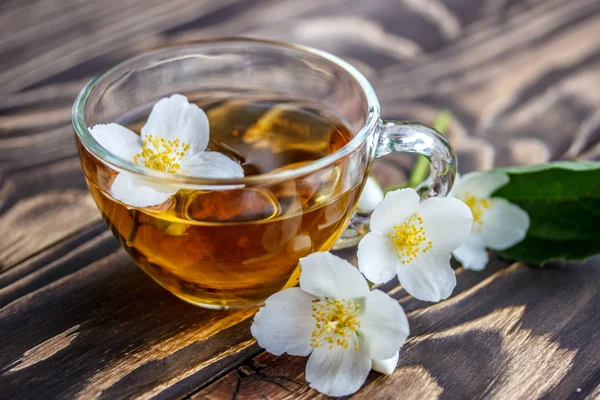 Yasemin çayı ve ahşap arka plan üzerinde Yasemin çiçekleri