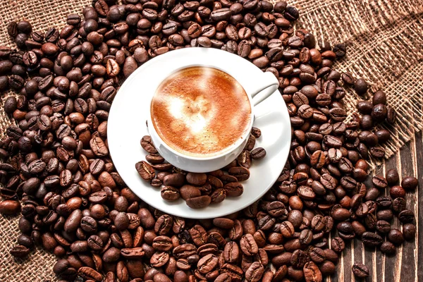 Xícara de grãos de café e café em uma placa de madeira velha — Fotografia de Stock