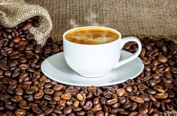 Xícara de café e grãos de café no fundo de madeira. — Fotografia de Stock