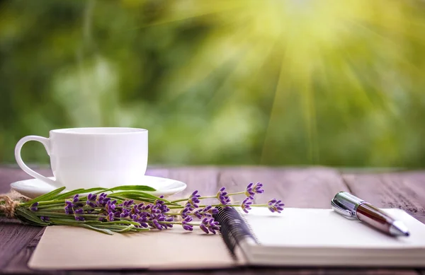 Cuaderno blanco en blanco, flores y taza de café en el escritorio — Foto de Stock